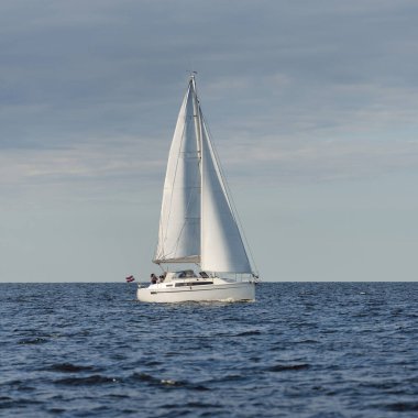 Baltık Denizi 'nde yelkenli bir yat. Gün batımı. Fırtınadan sonra dramatik bir gökyüzü, yumuşak güneş ışığı. Ulaşım, seyahat, seyahat, yat yarışı, spor, eğlence, eğlence, eğlence, yaşam tarzı, aile.