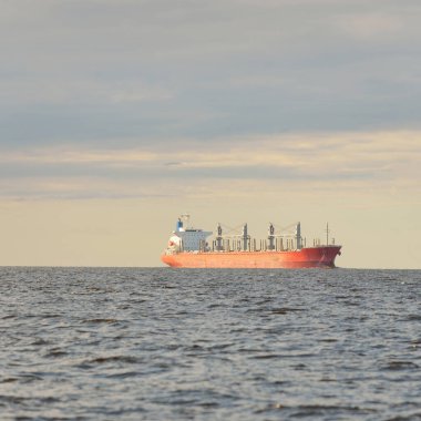 Büyük kırmızı bir yük gemisi (179 metre uzunluğunda) açık bir Baltık Denizi 'nde yüzüyor. Dramatik bir gökyüzü. Yük taşımacılığı, denizcilik gemisi, lojistik, küresel iletişim, ekonomi, iş dünyası, sanayi
