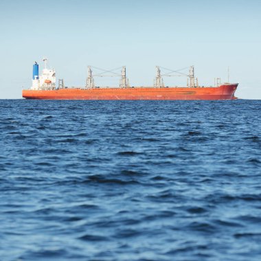 Büyük kırmızı bir yük gemisi (179 metre uzunluğunda) açık bir Baltık Denizi 'nde yüzüyor. Dramatik bir gökyüzü. Yük taşımacılığı, denizcilik gemisi, lojistik, küresel iletişim, ekonomi, iş dünyası, sanayi