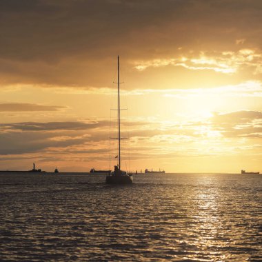 Baltık Denizi 'nde yelkenli bir yat. Gün batımı. Fırtınadan sonra dramatik bir gökyüzü, altın güneş ışığı. Ulaşım, seyahat, gezi, yat yarışı, spor, eğlence, boş zaman aktivitesi, yaşam tarzı