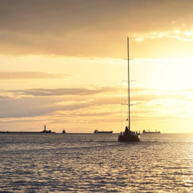 Baltık Denizi 'nde yelkenli bir yat. Gün batımı. Fırtınadan sonra dramatik bir gökyüzü, altın güneş ışığı. Ulaşım, seyahat, gezi, yat yarışı, spor, eğlence, boş zaman aktivitesi, yaşam tarzı