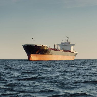 Büyük bir kargo gemisi (kimyasal tanker, 184 metre uzunluğunda) gün batımında açık denizde yol alır. Altın güneş ışığı. Yük taşımacılığı, yakıt, enerji üretimi, denizcilik gemisi, lojistik, ekonomi, sanayi