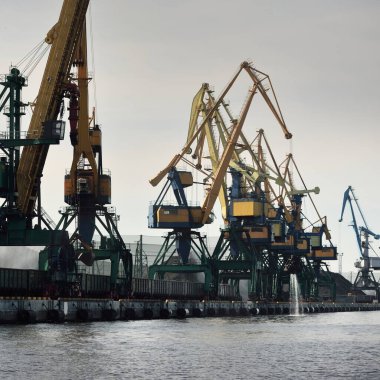Riga, Letonya 'daki modern kömür terminali. Vinçler yakın plan. Baltık Denizi. Nakliye, lojistik, küresel iletişim, ekonomi, iş, endüstri, tedarik, özel ekipman. Şehir manzarası