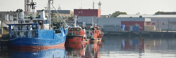 Fishing (trawler) and pilot boats moored to a pier in cargo port terminal. Nautical vessel, transportation, industry, repair, service