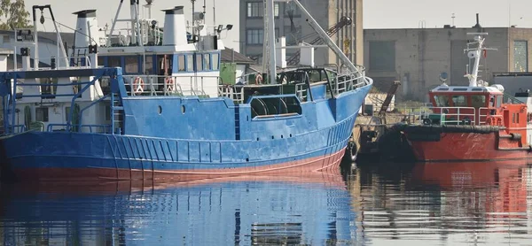 Fishing (trawler) and pilot boats moored to a pier in cargo port terminal. Nautical vessel, transportation, industry, repair, service