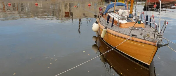 Modern klasik ahşap İsveçli yelkenli teknesi yat limanındaki bir iskeleye demirlemiş. Turizm, tatiller, boş zaman aktiviteleri, eğlence, yelkencilik temaları