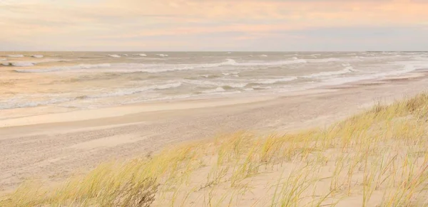 Baltic sea coast (sand dunes) after the storm at sunset. Clear sky, glowing clouds, wind. Autumn landscape. Nature, environmental conservation, ecology, ecotourism, local travel