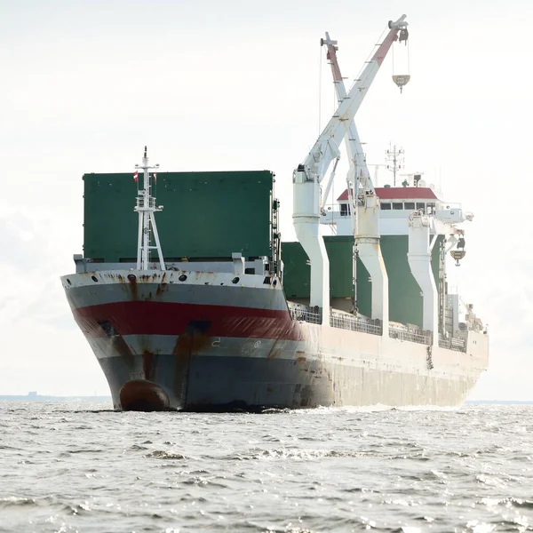 Large modern general cargo crane ship (142 meters length) sailing in an open sea. Freight transportation, nautical vessel, logistics, global communications, economy, business, industry. Panoramic view