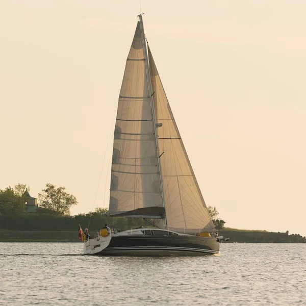 Günbatımında Baltık Denizi 'nde yelkenli yelkenli yelkenli. Fırtınadan sonra gökyüzü açık, altın güneş ışığı. Ulaşım, seyahat, gezi, spor, eğlence, boş zaman aktivitesi, yarış, yelkenli yarışı