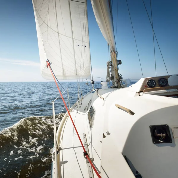 Günbatımında Baltık Denizi 'nde yelkenli yelkenli yelkenli. Kokpitten pruvaya, direğe ve yelkenlere bakın. Ulaşım, seyahat, gezi, spor, eğlence, boş zaman aktivitesi, yelkenli yarışı
