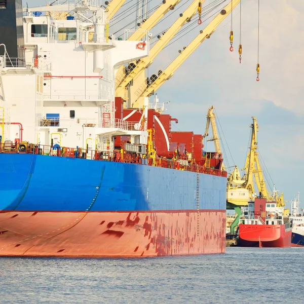 Büyük kargo gemisi (toplu taşıyıcı, 187 metre uzunluğunda) iskele terminalinde yükleme, arka planda vinçler. Yük taşımacılığı, lojistik, küresel iletişim, ekonomi, ticaret, sanayi