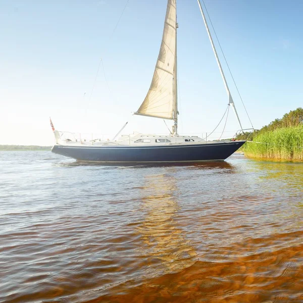 Kumlu kıyıya demirli mavi şalopeli yat (kumsalda otlarla kaplanmış). İsveç 'te, Avrupa' da. Doğa, yaz tatilleri, eğlence, gezi, spor, ulaşım, eko-turizm