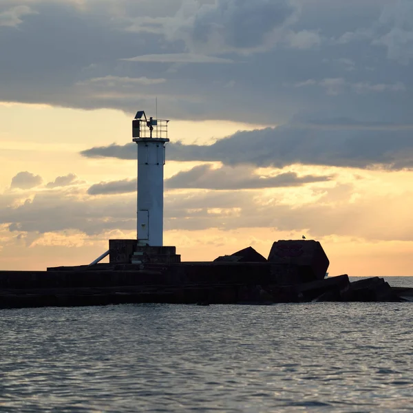 Güneş pilli deniz feneri. Baltık Denizi. Fırtınadan sonra dramatik günbatımı gökyüzü. Parlayan bulutlar, altın güneş ışığı. Umut ve barışın sembolü. Mimarlık, seyahat yerleri, navigasyon, yelkencilik.