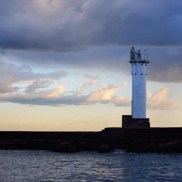 Güneş pilli deniz feneri. Baltık Denizi. Fırtınadan sonra dramatik günbatımı gökyüzü. Parlayan bulutlar, altın güneş ışığı. Umut ve barışın sembolü. Mimarlık, seyahat yerleri, navigasyon, yelkencilik.