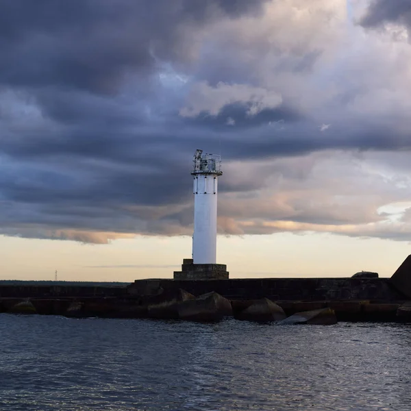 Güneş pilli deniz feneri. Baltık Denizi. Fırtınadan sonra dramatik günbatımı gökyüzü. Parlayan bulutlar, altın güneş ışığı. Umut ve barışın sembolü. Mimarlık, seyahat yerleri, navigasyon, yelkencilik.