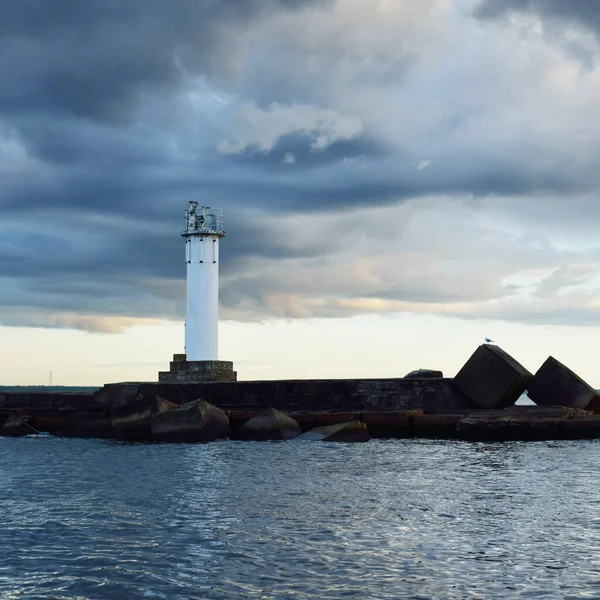 Güneş pilli deniz feneri. Baltık Denizi. Fırtınadan sonra dramatik günbatımı gökyüzü. Parlayan bulutlar, altın güneş ışığı. Umut ve barışın sembolü. Mimarlık, seyahat yerleri, navigasyon, yelkencilik.