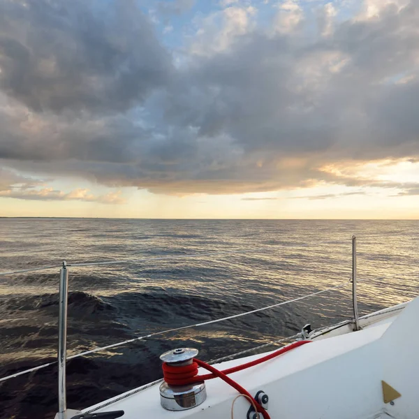Baltic sea after the storm, panoramic view from a sailing boat. Mast winch close-up. Dramatic sunset sky, glowing clouds. Idyllic seascape. Nature, cruise, travel destinations, recreation