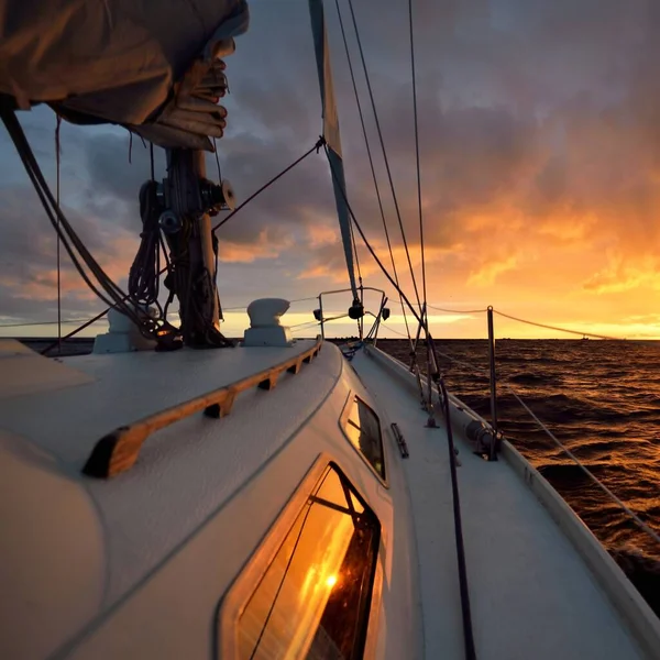 夕日の海で白いヨットセーリング デッキから弓 マスト 帆への眺め 壮大な雲の風景 嵐の後に輝く黄金の雲と劇的な空 レーシング スポーツ レジャー活動 — ストック写真