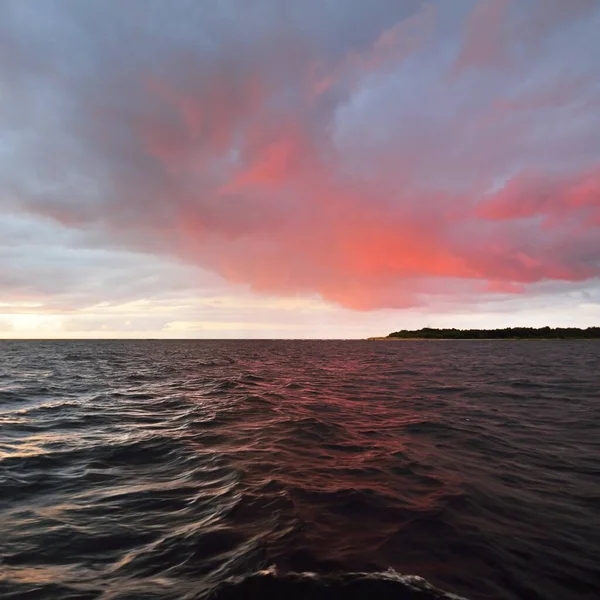 Dramatic sunset sky above the sea. Colorful glowing golden and pink clouds, dark water. Sailing after the storm, a view from the yacht. Epic seascape. Long exposure. Nature, fickle weather, danger