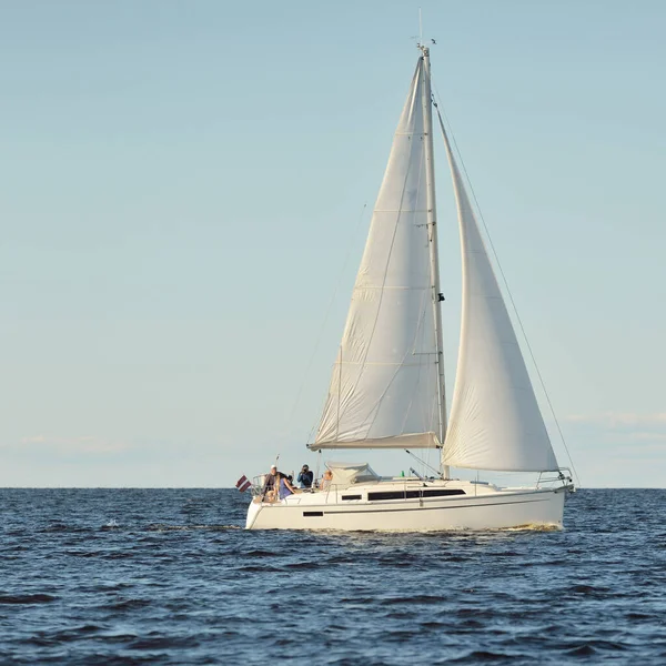 Baltık Denizi 'nde yelkenli bir yat. Gün batımı. Fırtınadan sonra dramatik bir gökyüzü, yumuşak güneş ışığı. Ulaşım, seyahat, seyahat, yat yarışı, spor, eğlence, eğlence, eğlence, yaşam tarzı, aile.