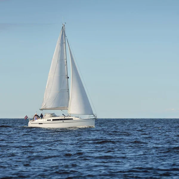 Sloop rigged yacht sailing in the Baltic sea. Sunset. Dramatic sky after the storm, soft sunlight. Transportation, travel, cruise, yachts racing, sport, recreation, leisure activity, lifestyle, family