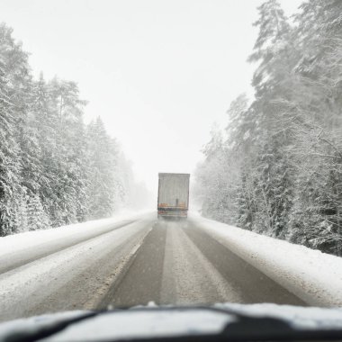 Boş otoyol (asfalt yol) karla kaplı ormanın içinden, kırsal alanda. Arabadan bak. Avrupa. Doğa, Noel tatilleri, uzak yerler, kış lastikleri, tehlikeli sürüş konsepti
