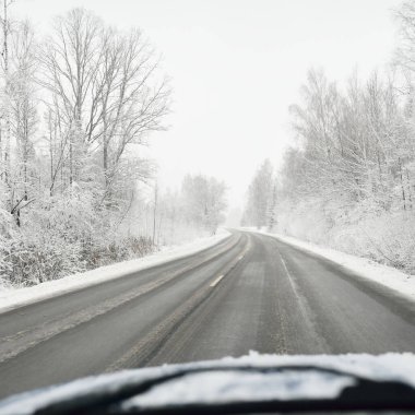 Boş otoyol (asfalt yol) karla kaplı ormanın içinden, kırsal alanda. Arabadan bak. Avrupa. Doğa, Noel tatilleri, uzak yerler, kış lastikleri, tehlikeli sürüş konsepti