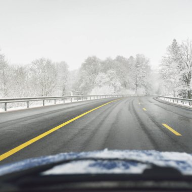 Karla kaplı ormanda boş otoyol (asfalt yol). Kanada mı? Doğa, Noel tatilleri, uzak yerler, kış lastikleri, tehlikeli sürüş konsepti