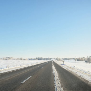 Karla kaplı orman ve kırsal alanda boş otoyol (asfalt yol). Kar sürükleniyor. Avrupa. Doğa, Noel tatilleri, uzak yerler, kış lastikleri, tehlikeli sürüş konsepti