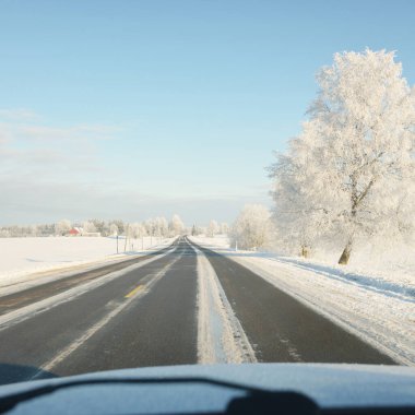 Karla kaplı orman ve kırsal alanda boş otoyol (asfalt yol). Kar sürükleniyor. Avrupa. Doğa, Noel tatilleri, uzak yerler, kış lastikleri, tehlikeli sürüş konsepti