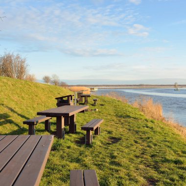 Modern dinlenme alanı, orman parkı, göl. Tahta banklar, masalar. Kamp alanı. Yumuşak güneş ışığı, açık gökyüzü. Baharın başında. Idyllic manzara. Doğa, çevre, ekoloji, eko-turizm, tatiller, hafta sonu