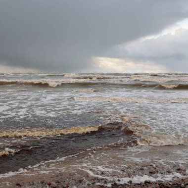 Gün batımında Baltık kıyısı. Kumsal, kum tepeleri. Dramatik gökyüzü akan bulutlar. Yumuşak güneş ışığı. Doğa, hava, çevre, eko turizm