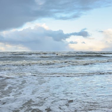 Fırtınadan sonra Baltık Denizi. Dramatik gökyüzü, parlayan bulutlar, yumuşak güneş ışığı. Dalgalar, su sıçratma. Resimli manzara, deniz manzarası, doğa. Panoramik görünüm