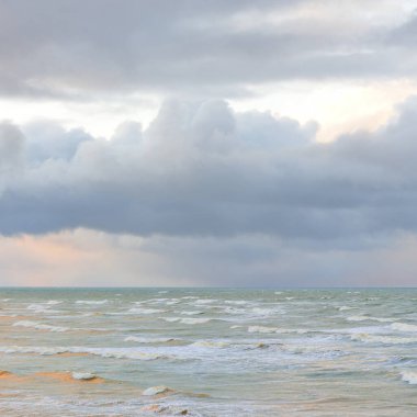 Fırtınadan sonra Baltık Denizi. Dramatik gökyüzü, parlayan bulutlar, yumuşak güneş ışığı. Dalgalar, su sıçratma. Resimli manzara, deniz manzarası, doğa. Panoramik görünüm