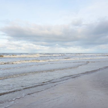 Kumlu bir sahilden (kum tepeleri) Baltık denizinin panoramik görüntüsü. Koyu bulutlu dramatik bir gökyüzü. Dalgalar, su sıçramaları. Idyllic deniz manzarası. Sıcak kış havası, iklim değişikliği, doğa. Danimarka