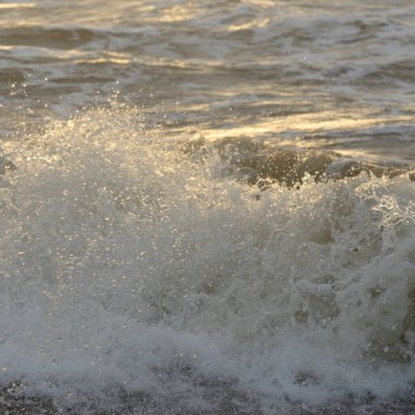 Fırtınadan sonra Baltık kıyıları. Gün batımı, yumuşak güneş ışığı. Su yüzeyi dokusu, çarpan dalgalar, sıçramalar, köpük. Resimli panoramik manzara. Idyllic deniz manzarası. Doğa, çevre, ekoloji temaları