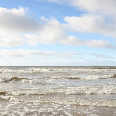 Fırtınadan sonra Baltık Denizi. Dramatik gökyüzü, parlayan bulutlar, yumuşak güneş ışığı. Dalgalar, su sıçratma. Resimli manzara, deniz manzarası, doğa. Panoramik görünüm