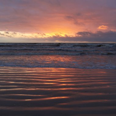 Fırtınadan sonra gün batımında Baltık Denizi. Dramatik gökyüzü, parlayan bulutlar, dofty altın güneş ışığı, dalgalar, fışkıran su. Resimli panoramik manzara. Doğa, çevre, ekoloji