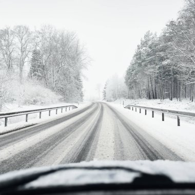 Boş otoyol (asfalt yol) karla kaplı ormanın içinden, kırsal alanda. Arabadan bak. Avrupa. Doğa, Noel tatilleri, uzak yerler, kış lastikleri, tehlikeli sürüş konsepti