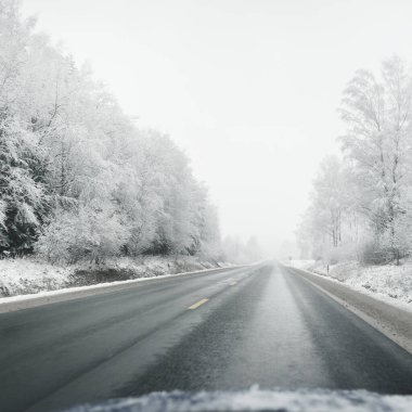 Boş otoyol (asfalt yol) karla kaplı ormanın içinden, kırsal alanda. Arabadan bak. Avrupa. Doğa, Noel tatilleri, uzak yerler, kış lastikleri, tehlikeli sürüş konsepti