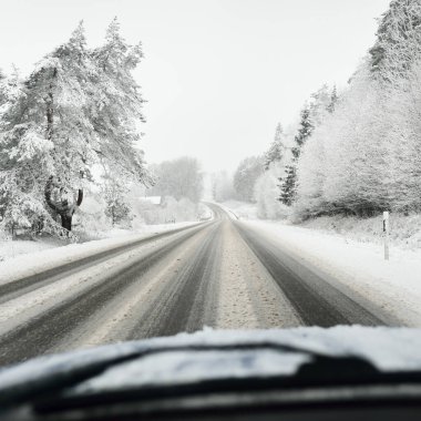 Boş otoyol (asfalt yol) karla kaplı ormanın içinden, kırsal alanda. Arabadan bak. Avrupa. Doğa, Noel tatilleri, uzak yerler, kış lastikleri, tehlikeli sürüş konsepti
