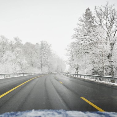 Karla kaplı ormanda boş otoyol (asfalt yol). Kanada mı? Doğa, Noel tatilleri, uzak yerler, kış lastikleri, tehlikeli sürüş konsepti
