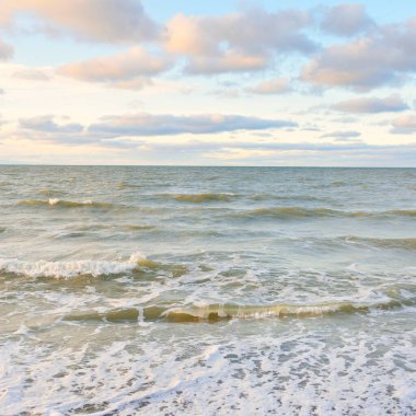Gün batımında Baltık kıyıları (kum tepeleri). Yumuşak güneş ışığı, parlayan bulutlar, dalgalar ve su fışkıran berrak gökyüzü. Idyllic deniz manzarası. Liepaja, Letonya, Avrupa. Sıcak kış havası, iklim değişikliği, doğa