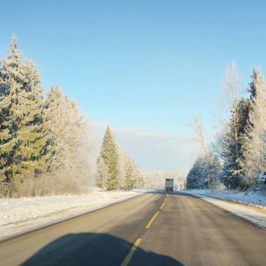 Karla kaplı orman ve kırsal alanda boş otoyol (asfalt yol). Kar sürükleniyor. Avrupa. Doğa, Noel tatilleri, uzak yerler, kış lastikleri, tehlikeli sürüş konsepti