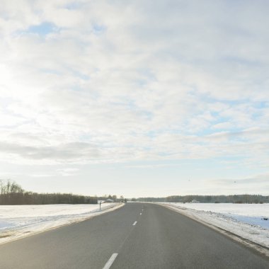 Karla kaplı orman ve kırsal alanda boş otoyol (asfalt yol). Kar sürükleniyor. Avrupa. Doğa, Noel tatilleri, uzak yerler, kış lastikleri, tehlikeli sürüş konsepti