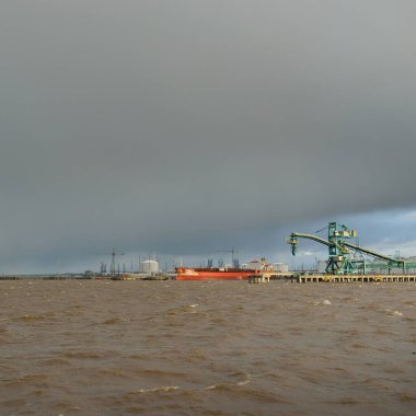 Kargo limanına demir atmış büyük bir gemi. Tahıl doldurucu vinç. Baltık Denizi. Küresel iletişim, lojistik, endüstri