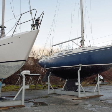 Mavi yelkenli donanımlı yelkenli bir yat kulübünde karada duruyor. Hizmet, onarım, ulaşım, spor, eğlence, eğlence aktivitesi