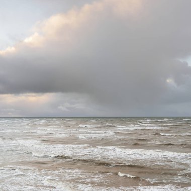 Fırtınadan sonra Baltık Denizi. Dramatik gökyüzü, parlayan bulutlar, yumuşak güneş ışığı. Dalgalar, su sıçratma. Resimli manzara, deniz manzarası, doğa. Panoramik görünüm