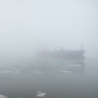 Donmuş nehir, büyük bir kargo gemisi. Kar, kalın sis. Kış kentsel manzarası kavramı. Ulaşım, denizcilik gemisi, küresel iletişim, endüstri, lojistik