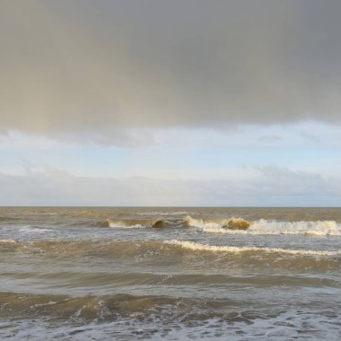 Kumlu bir sahilden (kum tepeleri) Baltık denizinin panoramik görüntüsü. Koyu bulutlu dramatik bir gökyüzü. Dalgalar, su sıçramaları. Idyllic deniz manzarası. Sıcak kış havası, iklim değişikliği, doğa. Danimarka